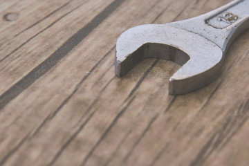 old silver metal wrench lies on a wooden plank table, macro