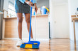 Afro woman sweeping floor with broom at home.