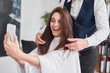 © gpointstudio - Beautiful woman with mobile phone making selfie in hair salon