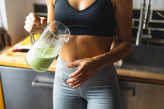 fitness diet concept. sporty woman drinking a green detox smoothie for breakfast in the kitchen.