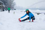 Fototapeta Panele - Young woman stretching arms on snowy day in the city