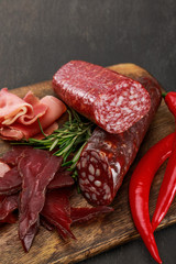 Wall Mural - close up view of delicious meat platter served with chili pepper and rosemary on wooden black table