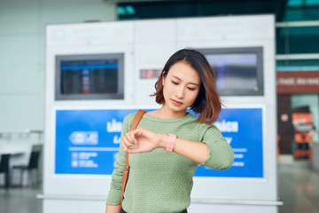 Beautiful asian woman looks at wristwatch for checking the time.