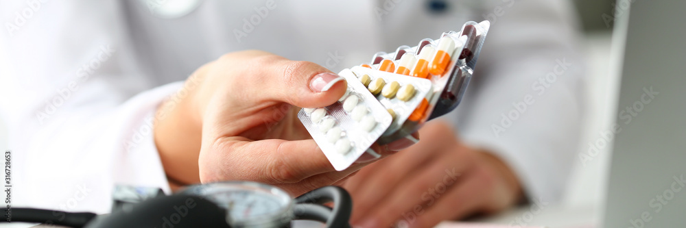 Female doctor hand holding pack of different tablet