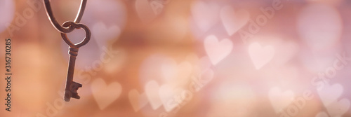 Fotografía Old rusty vintage key in the shape of a heart, panoramic bokeh background with copy space