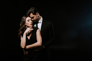 Wall Mural - sensual man standing with attractive woman in dress on black