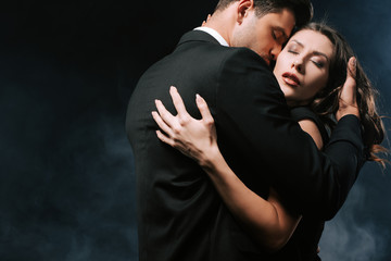 Wall Mural - passionate man hugging sensual woman on black with smoke