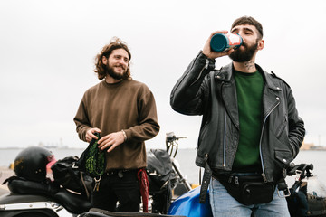 Photo of bearded young men bottle and smiling while standing