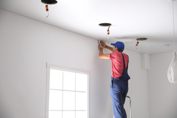 Poster - Worker installing stretch ceiling in empty room. Space for text