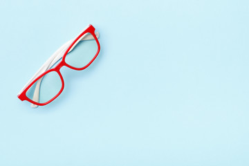 Modern trendy glasses in red frames on a blue background. Copy space