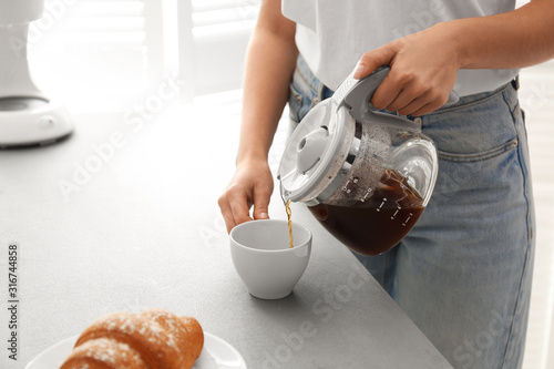 Fotografía Woman pouring coffee into cup at home, closeup. Morning routine