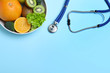 © New Africa - Fruits, vegetables and stethoscope on light blue background, flat lay with space for text. Visiting nutritionist