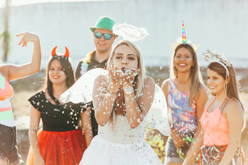 Wall Mural - Brazilian Carnival. Young woman in costume enjoying the carnival party blowing confetti