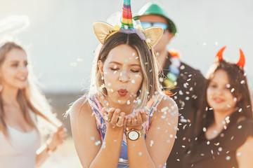 Wall Mural - Brazilian Carnival. Young woman in costume enjoying the carnival party blowing confetti