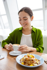 Wall Mural - Smiling asian woman having pancakes for breakfast