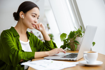 Smiling beautiful young asian woman working on laptop