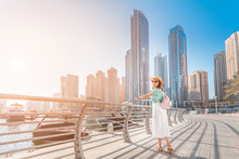 Cheerful Asian Traveler Girl Walking On A Promenade In Dubai Marina District. Travel Destinations And Tourist Lifestyle In UAE
