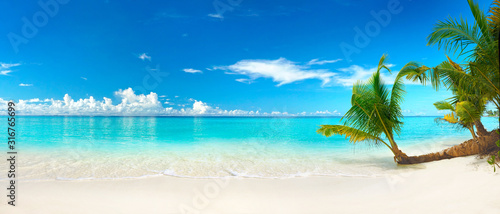 Fotografía Beautiful beach with white sand, turquoise ocean, blue sky with clouds and palm tree over the water on a Sunny day