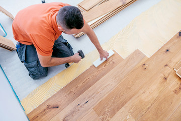 Wall Mural - Craftsman is laying parquet flooring in a modern new building