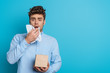 sick man sneezing in paper napkin while looking at camera on blue background