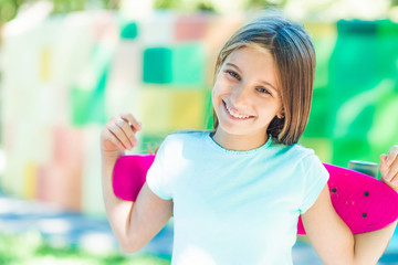 Wall Mural - Smiling teenage girl holding pink skateboard at the back