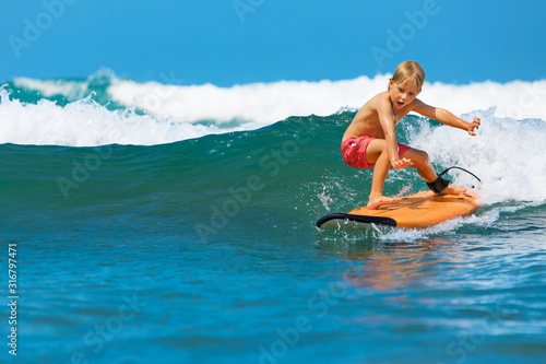 Happy boy - young surfer learning ride, jump from surfboard with fun, run to beach Canvas Print