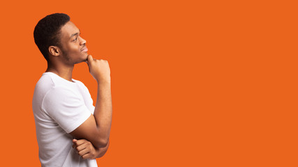 pensive afro man profile portrait on orange background