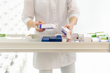 Wall Mural - Pharmacist holding medicine box and capsule pack in pharmacy drugstore.