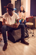 © Seventyfour - Full length portrait of trendy African man wearing hat and holding beer bottle while relaxing in music studio