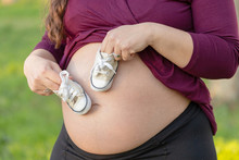 Pregnant Woman Playing With Baby Shoes