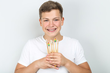 Young man holding toothbrushes on grey background