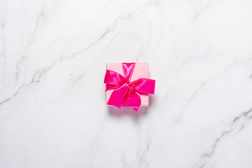 Wall Mural - Gift box with pink ribbon on a marble background. Concept of the holiday, gifts, Valentine's Day, Christmas and New Year. Flat lay, top view