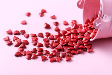 Wall Mural - Red heart shaped sprinkles with bucket on pink background