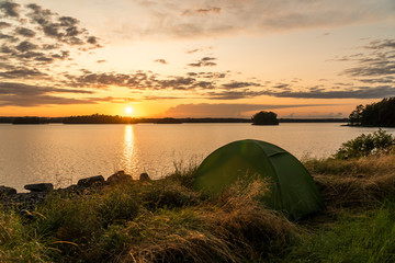 Wall Mural - Landscape shot of sunset at a beautiful lake in Sweden with islands and a tent in the forground