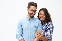 Smiling young couple using smartphone. Cheerful young man and woman standing together and using mobile phone on white background. Technology concept
