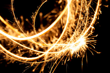 Wall Mural - Abstract pattern of sparks and bright light beams of Golden color on a black background