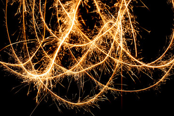 Abstract pattern of sparks and bright light beams of Golden color on a black background