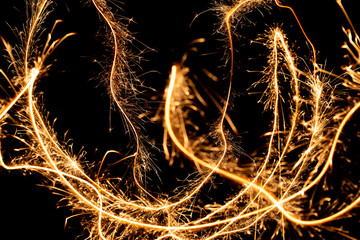 Wall Mural - Abstract pattern of sparks and bright light beams of Golden color on a black background