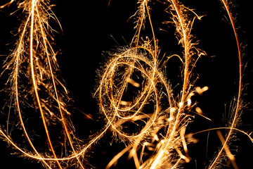 Wall Mural - Abstract pattern of sparks and bright light beams of Golden color on a black background