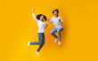 Cheerful girl and handsome guy jumping in air, having fun together