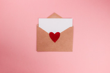 Love letter with white paper sheet in craft paper envelope with red heart flat lay on colorful pink background. 8 march, Mother's day, Valentine's Day template. Top view with copy space. Stock photo