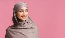 Attractive Muslim Woman In Hijab Looking Away Over Pink Background