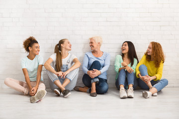 diverse women sitting on floor talking and smiling indoor