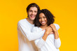 © Prostock-studio - Romantic multiracial couple embracing, posing together over yellow background in studio