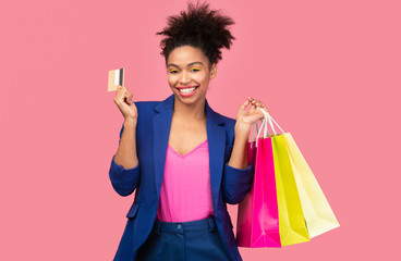 Cheerful black woman with shopping bags and plastic card