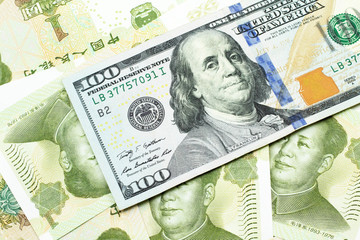 A macro image of a new, blue American one dollar bill close up on a background of Chinese one yuan bills from the United States