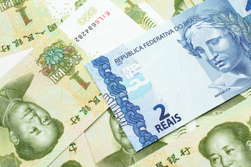 A blue two reais bank note from Brazil close up in macro with a background of United States one dollar bills