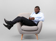 © Pixel-Shot - African-American man with mobile phone relaxing in armchair against grey background