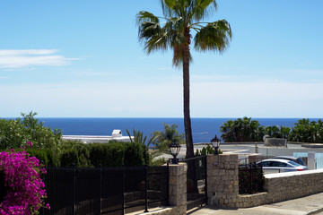 Luxury house on a coast with cars, trees, road and yacht view. Ibiza island, Spain