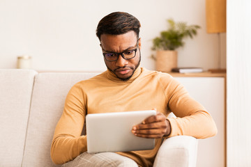 Poster - Serious Entrepreneur Using Digital Tablet Sitting On Sofa At Home